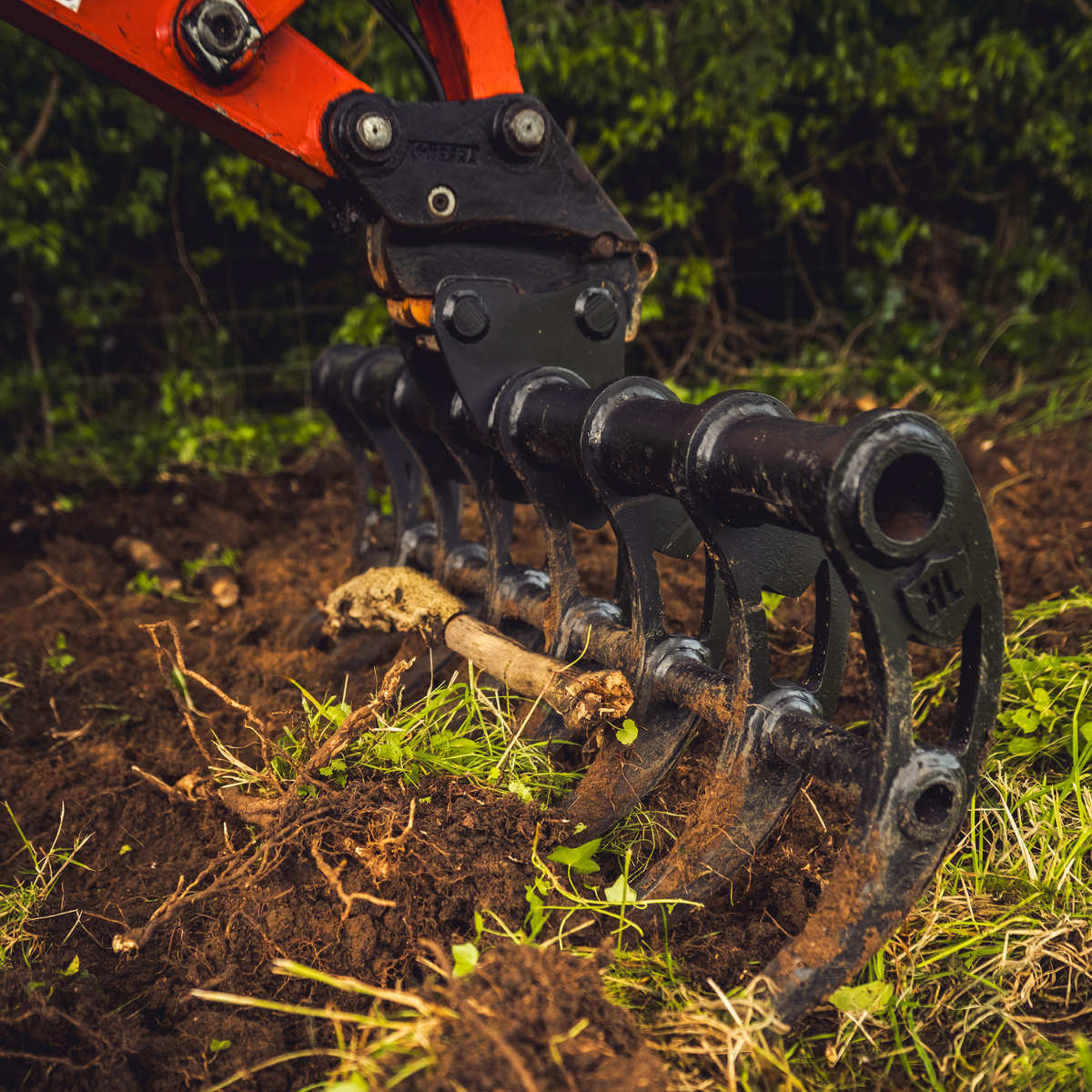 Hardlife Root Rake shown removing roots from ground
