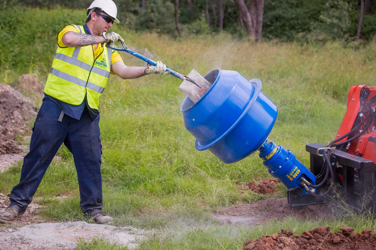 Worker using Auger Torque Cement Mixer Bowl for Earth Drills on-site for mixing cement.