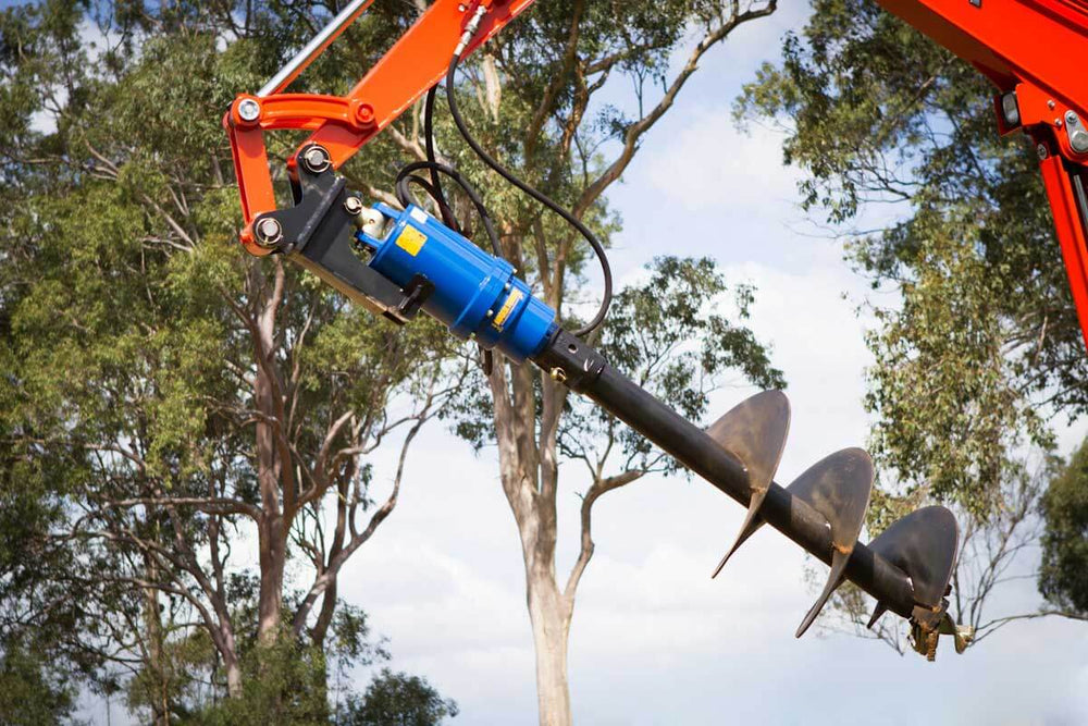Auger S5- 75mm Sq- Length 1500mm attached to heavy machinery in a tree-rich environment.